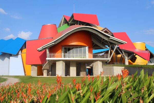 A colorful building with a large roof and a grassy area.