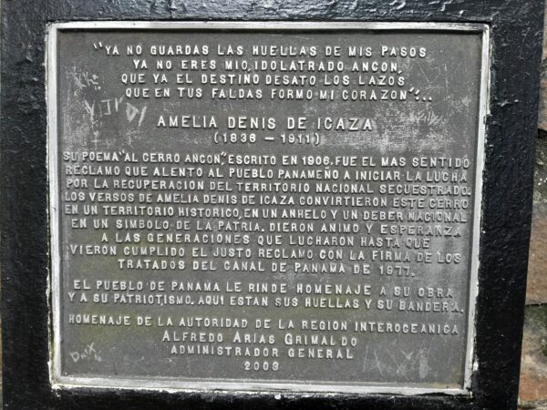 A plaque in spanish is shown on the side of a building.