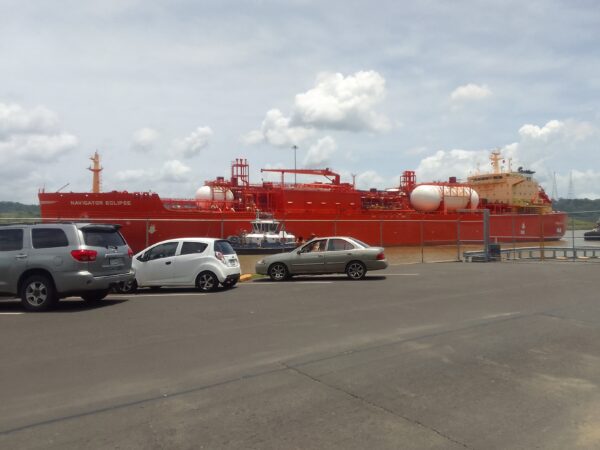 A red tanker ship with cars parked in front of it.