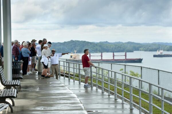 A group of people standing on the side of a pier.