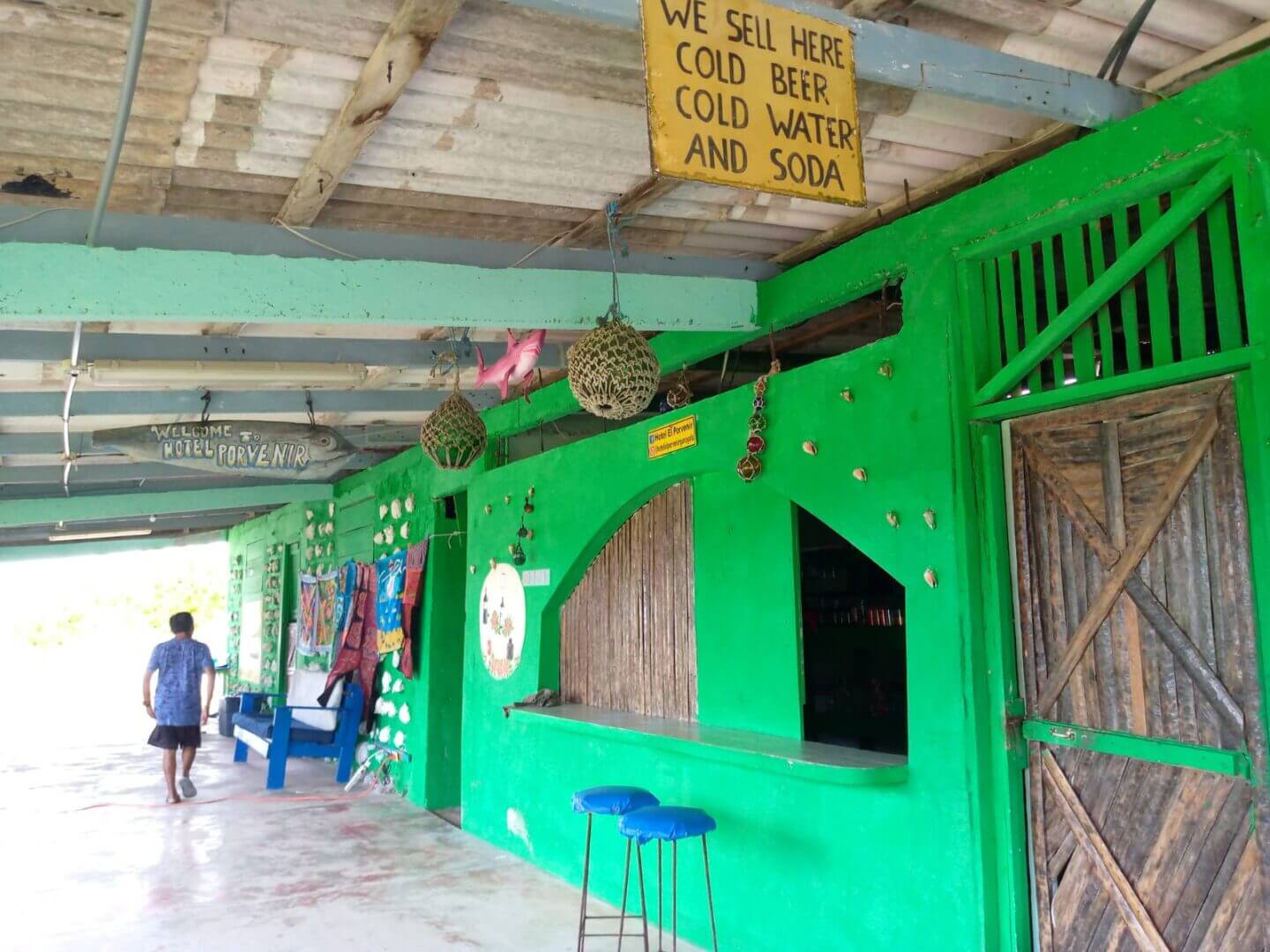 A green-painted building with open windows and people walking by.