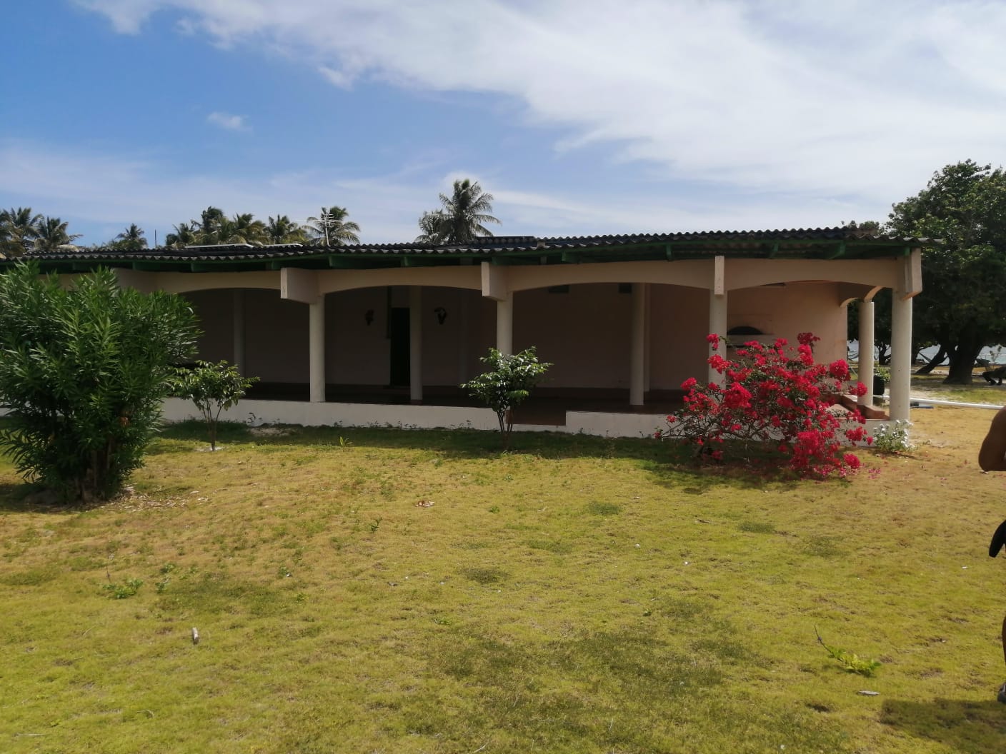 Single-story house with front porch and garden under a blue sky.