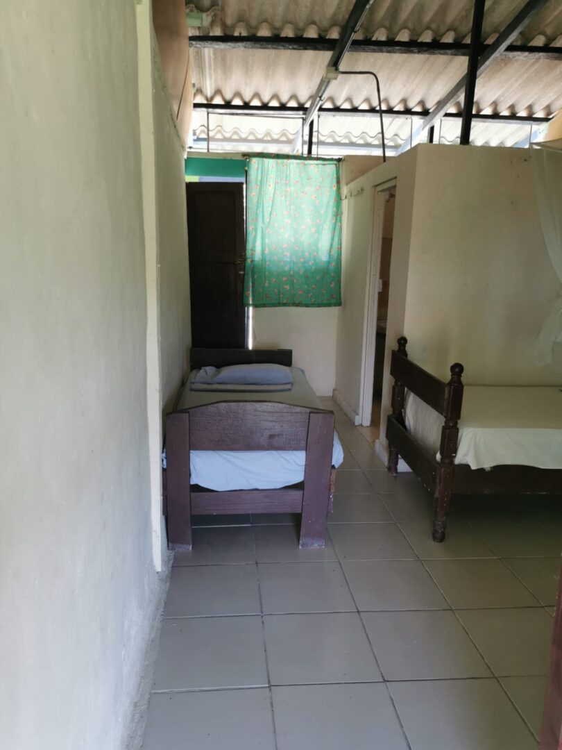Simple room with two single beds and a green curtain.