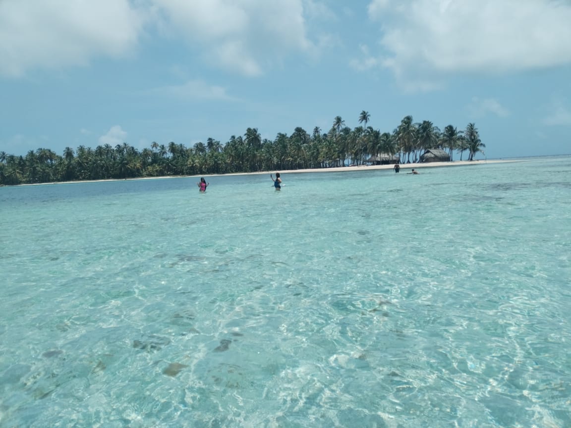 People enjoying clear, shallow ocean water near a tropical island.