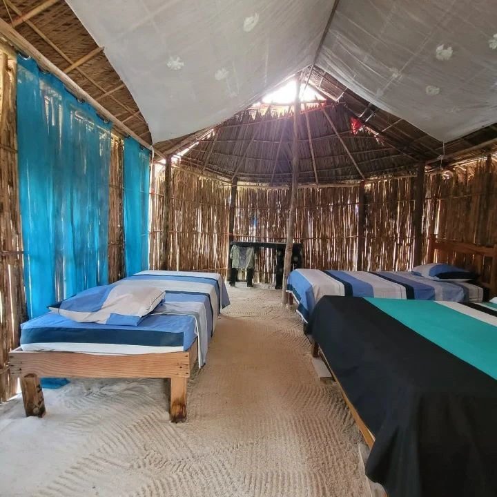 Cozy wooden room with beds and a table under a peaked ceiling.