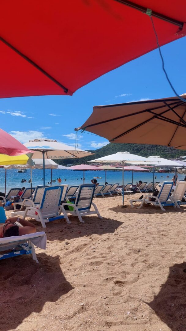 Beach scene with umbrellas and lounge chairs by the sea.