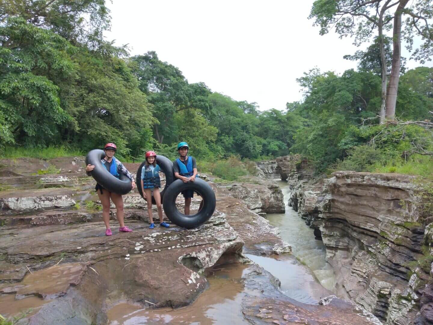 Three people with life jackets on a river.