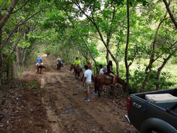 A group of people riding horses down a dirt road.