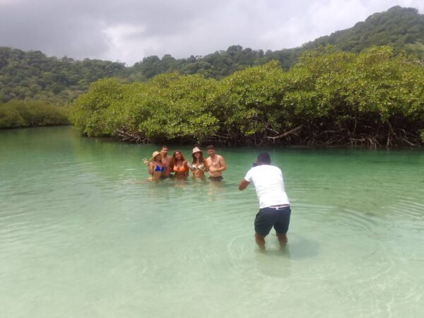 A group of people in the water with a man taking pictures.