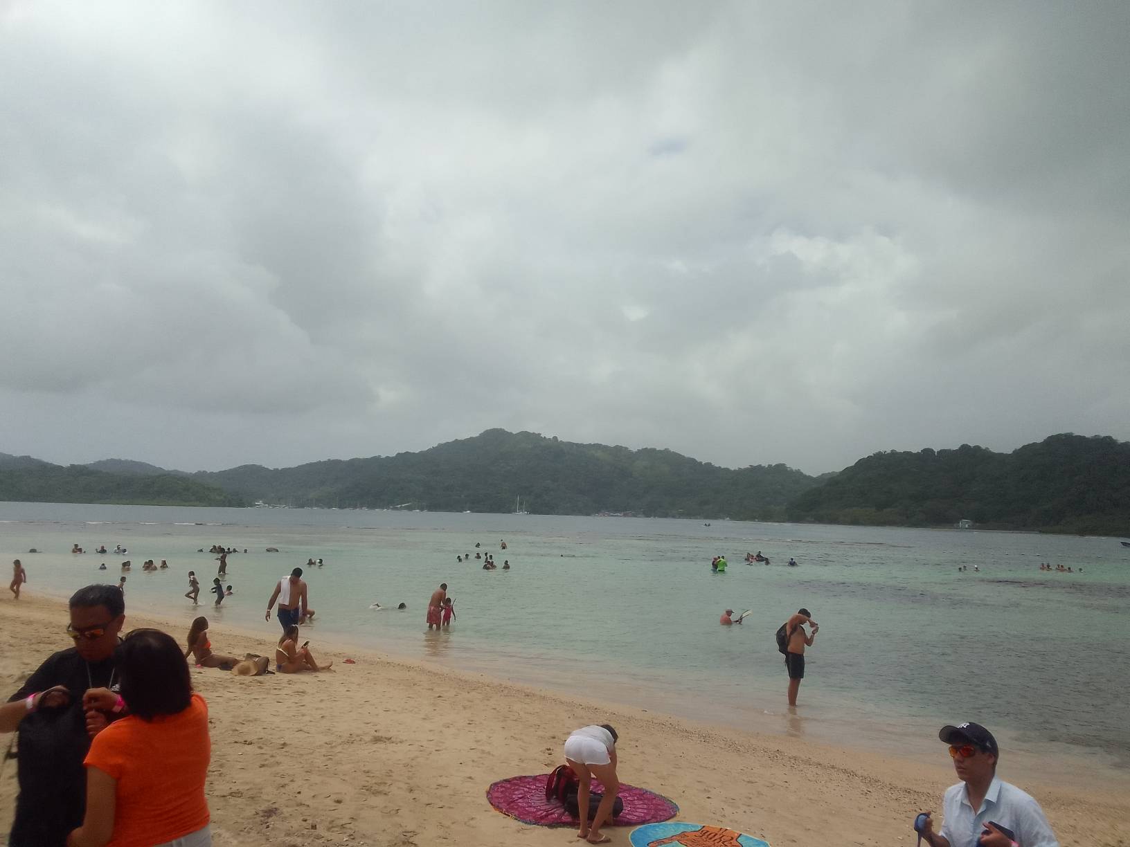 A beach with people swimming and playing in the water.