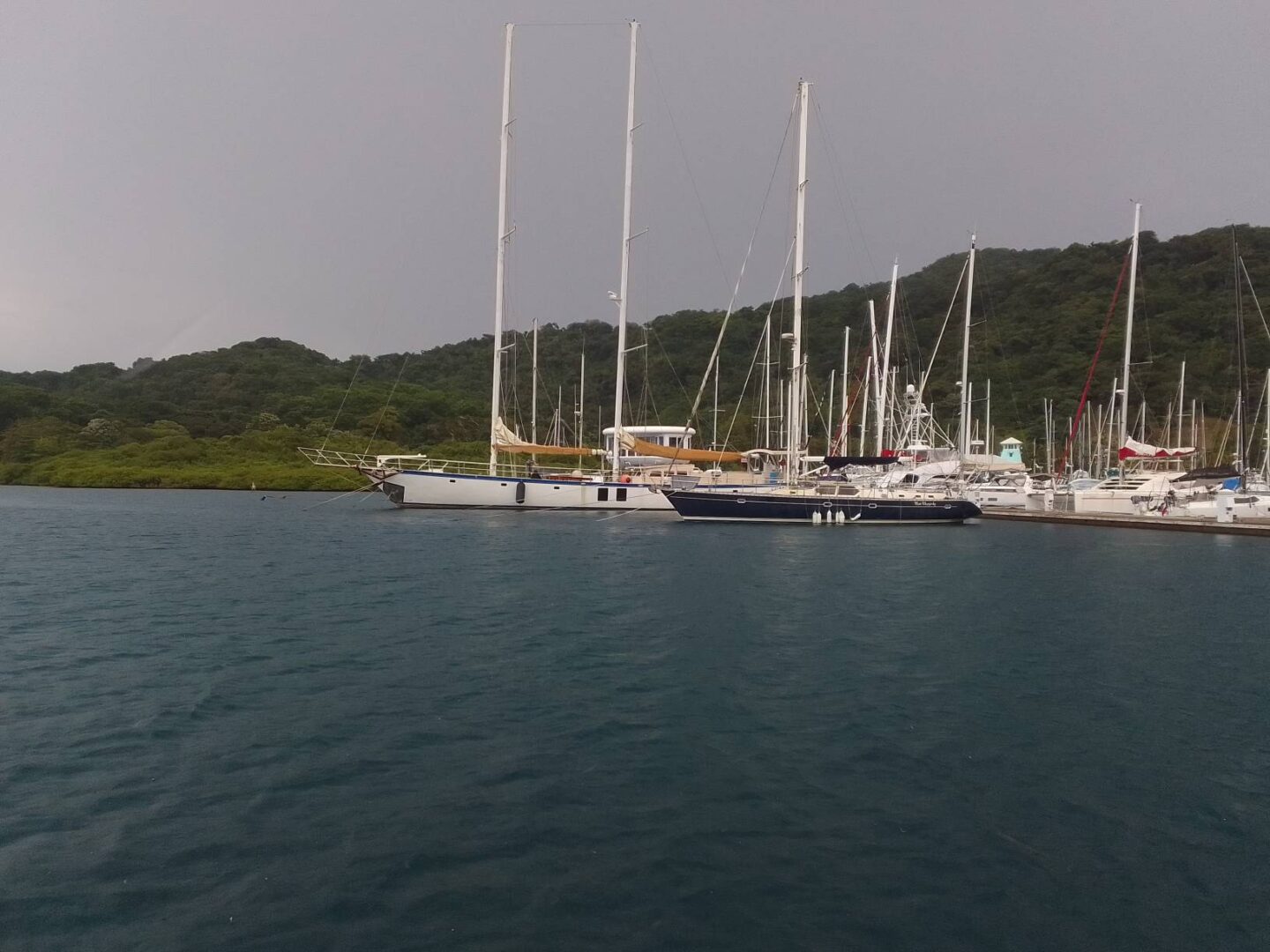 A group of boats in the water near some hills.