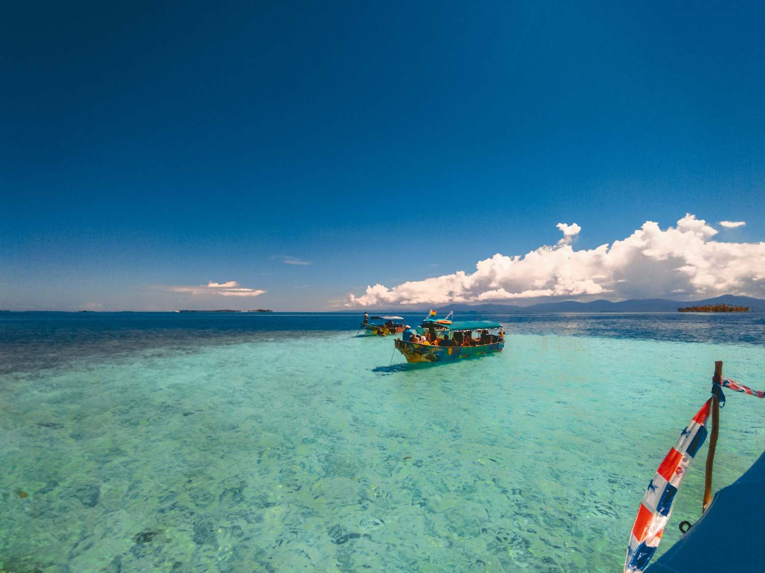 A boat floating on top of the ocean under a blue sky.