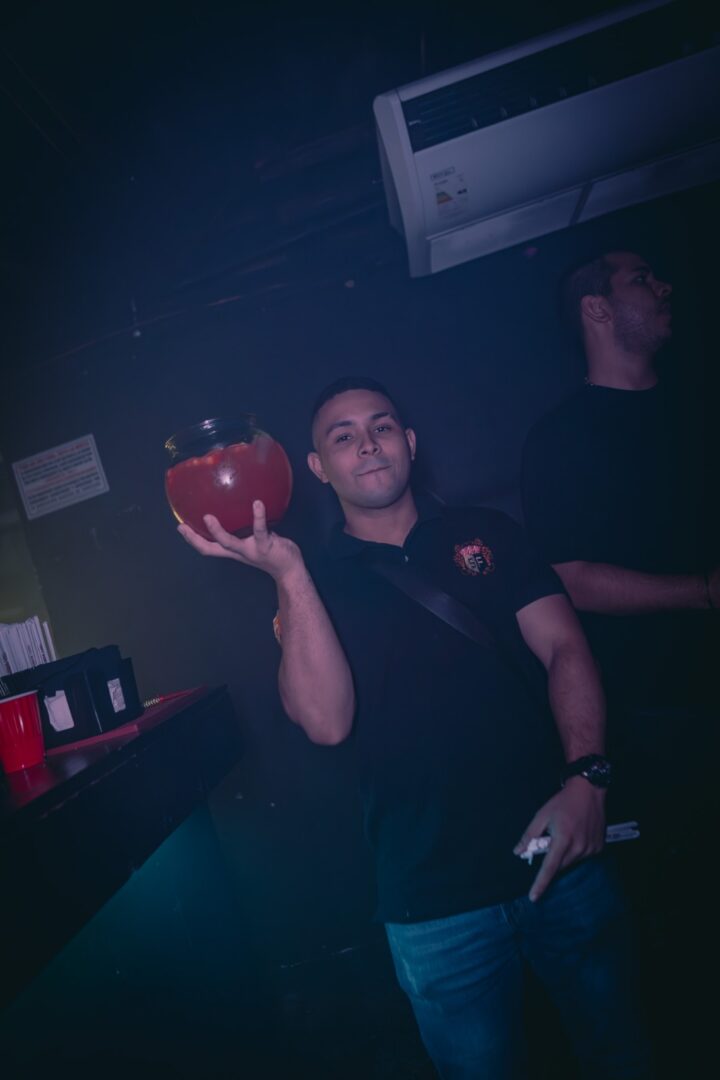 Man holding a large cocktail bowl in a dimly lit bar.