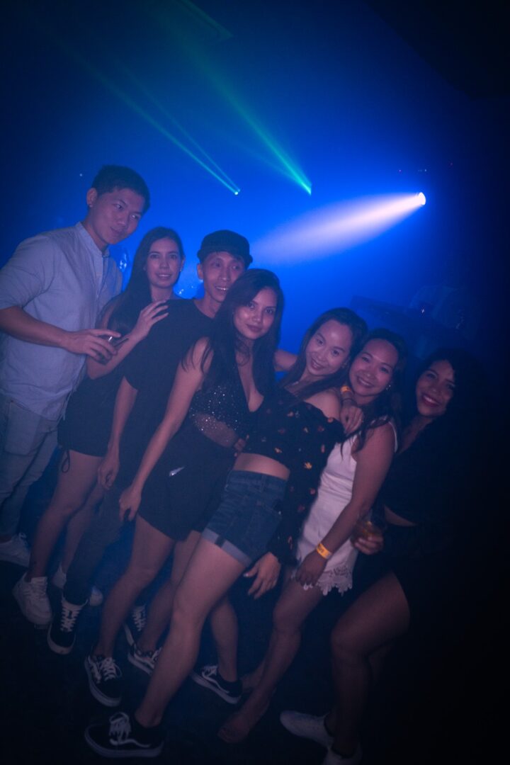 Group of friends enjoying a night out with blue club lights.