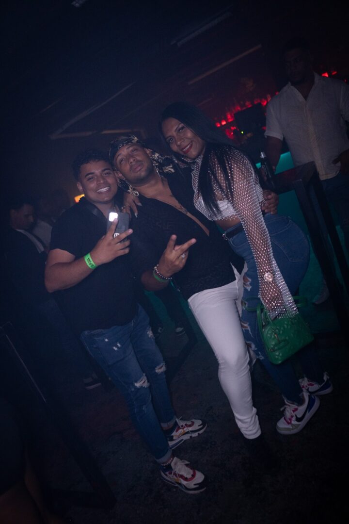 Three friends posing happily at a dimly lit party or club.