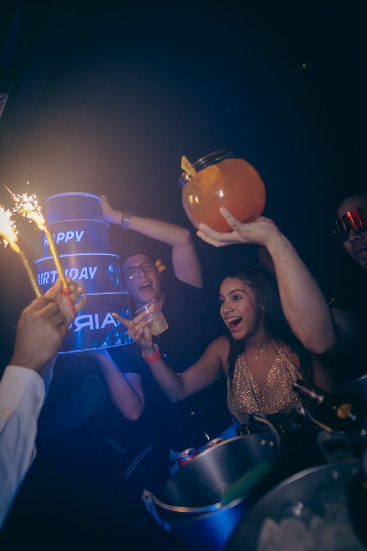 Friends celebrating with sparklers and drinks at a lively nighttime party.