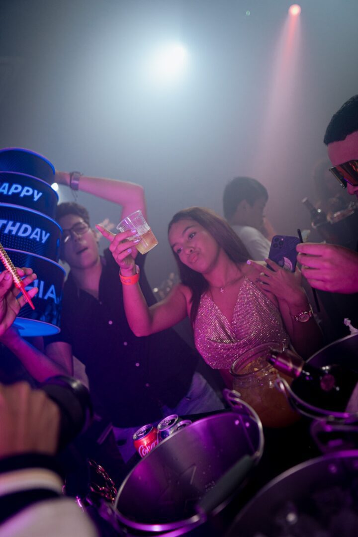 Friends celebrating a birthday with drinks in a lively party atmosphere.