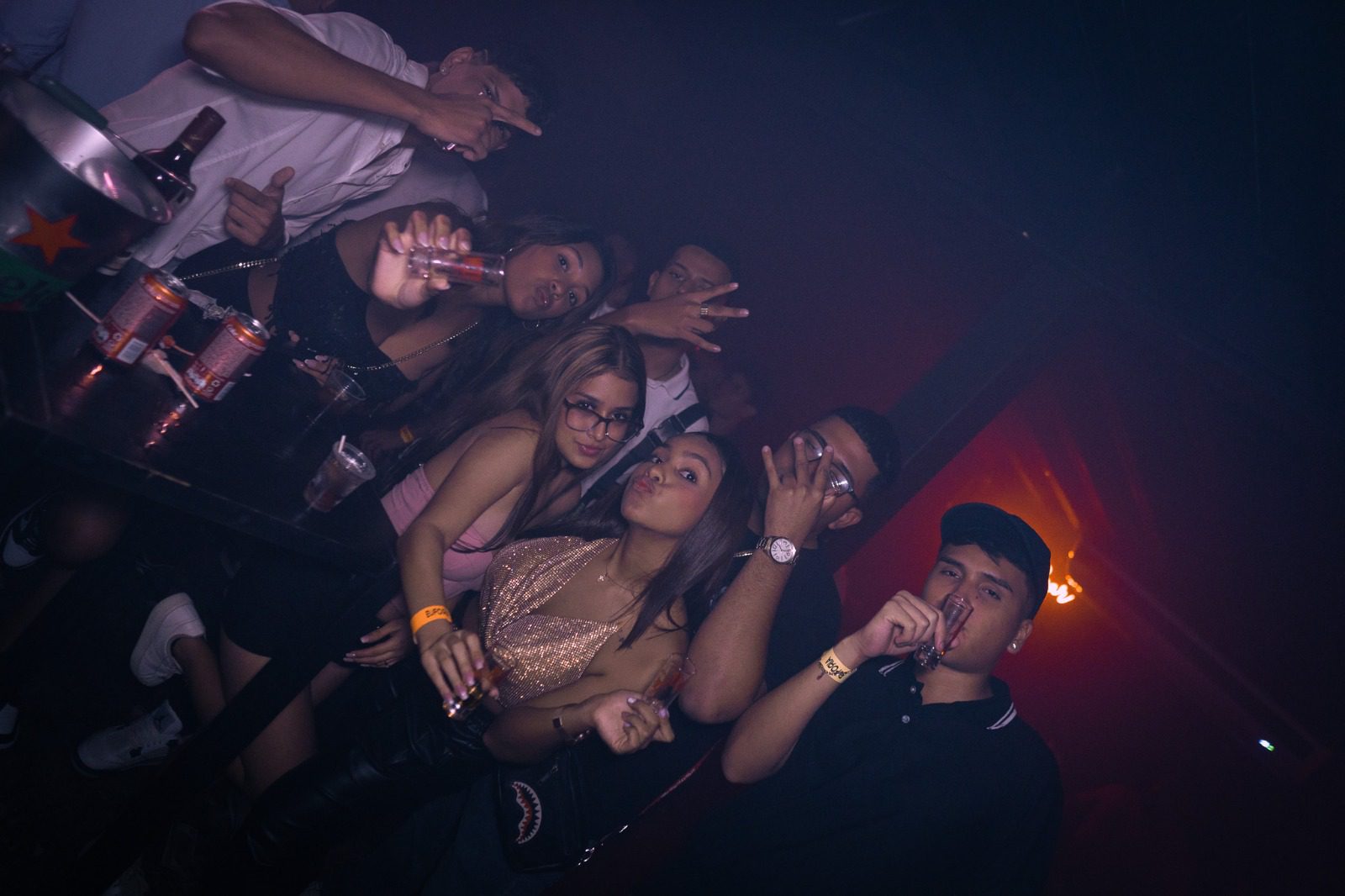 A group of friends enjoying a night out at a club with drinks and dim lighting.