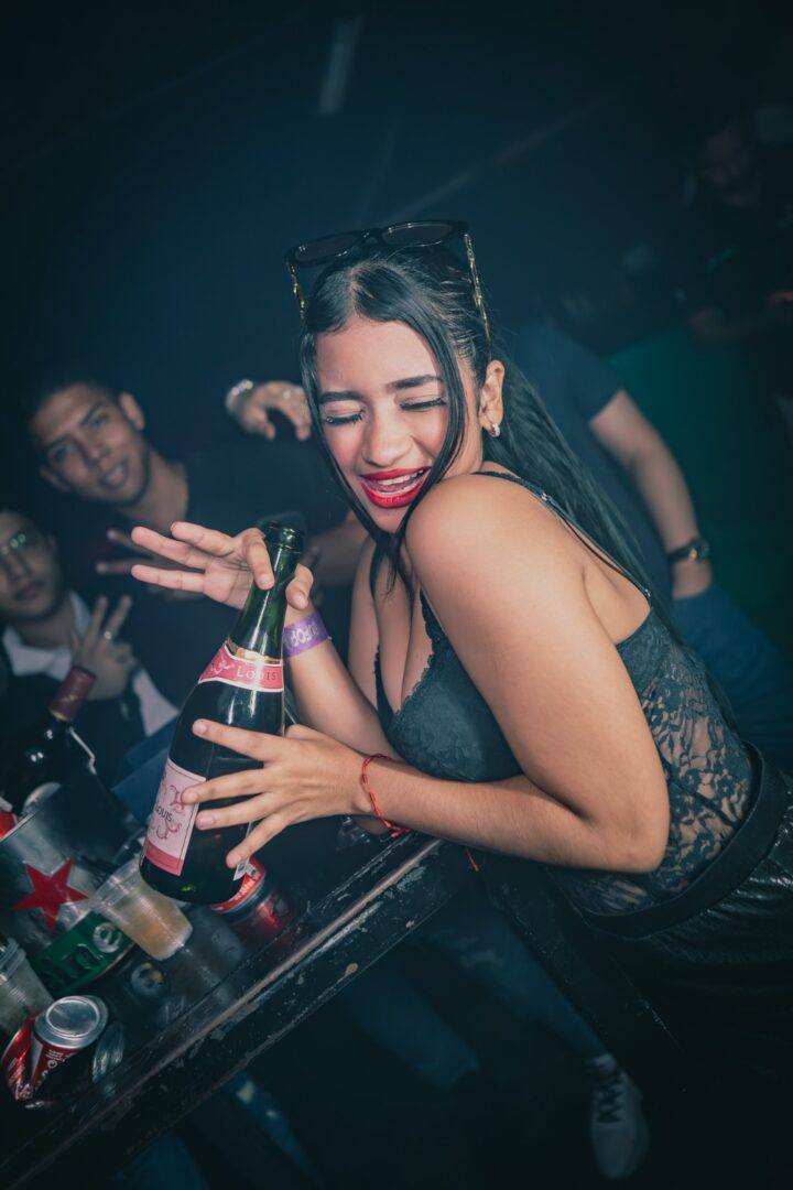 A joyful woman dancing and holding a drink at a lively party.