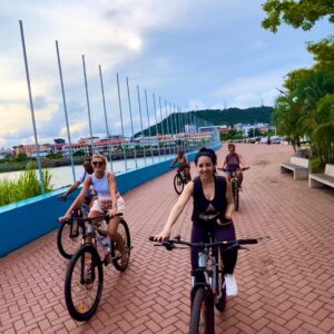 Group of friends biking along a waterfront promenade on a cloudy day.