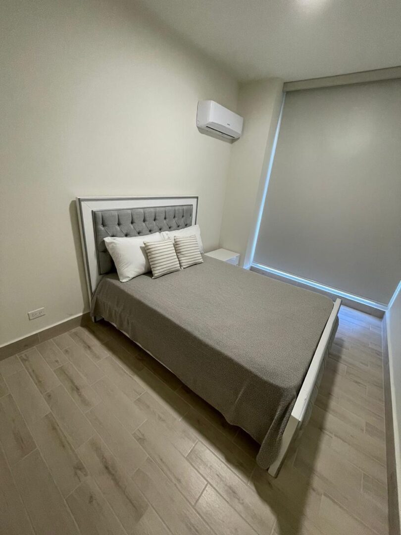 Minimalist bedroom with a neatly made bed and a window blind.
