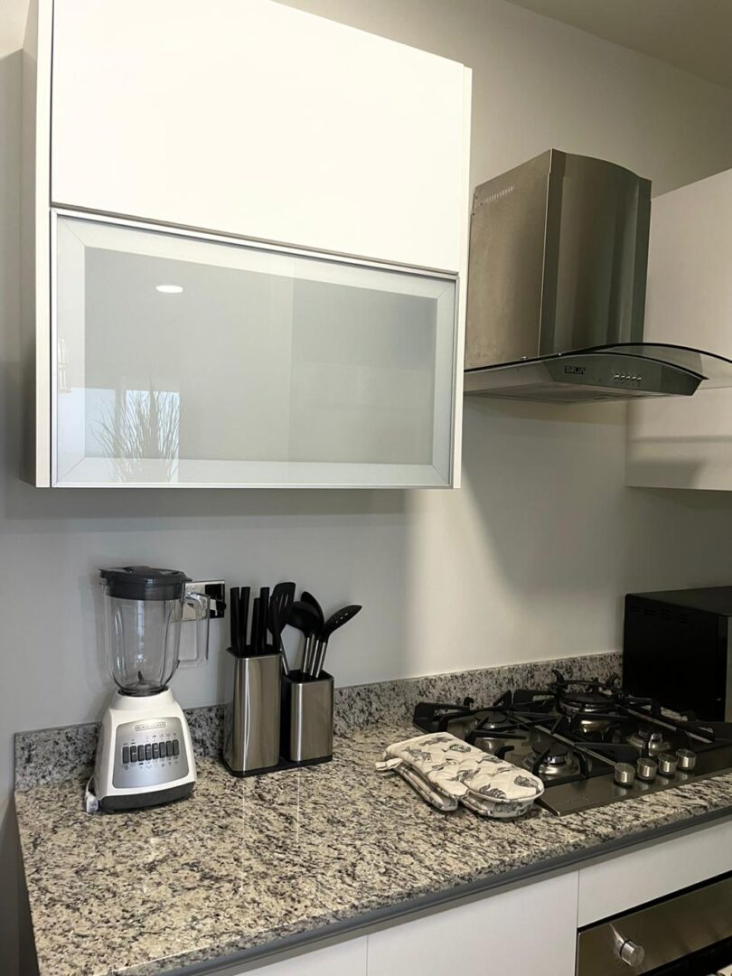 Modern kitchen corner with blender, knife set, and gas stove.