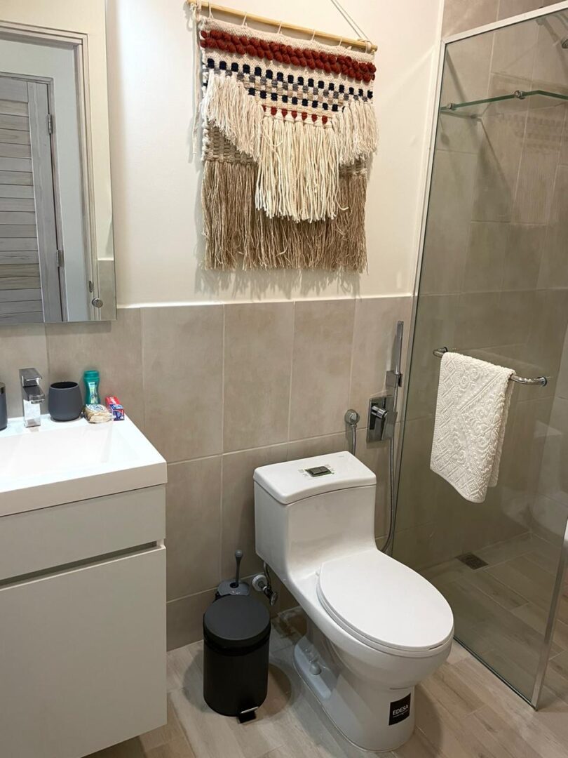 Compact bathroom with white vanity, toilet, and glass shower enclosure.