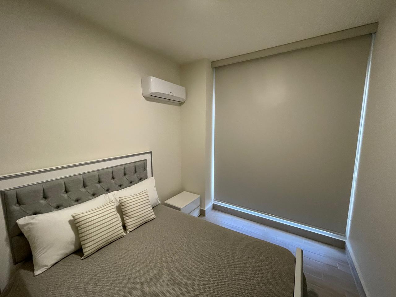 Minimalist bedroom with a gray bed and large window blinds.