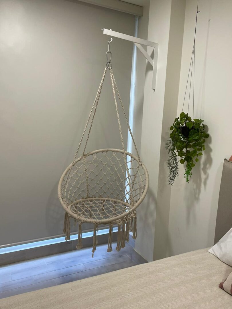 A cozy hanging wicker chair in a minimalist room corner.