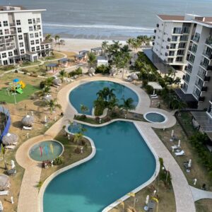 Aerial view of a modern beachfront resort with pools and playground.