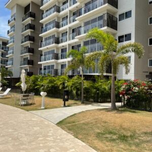 Modern apartment building with balconies and palm trees under a clear sky.