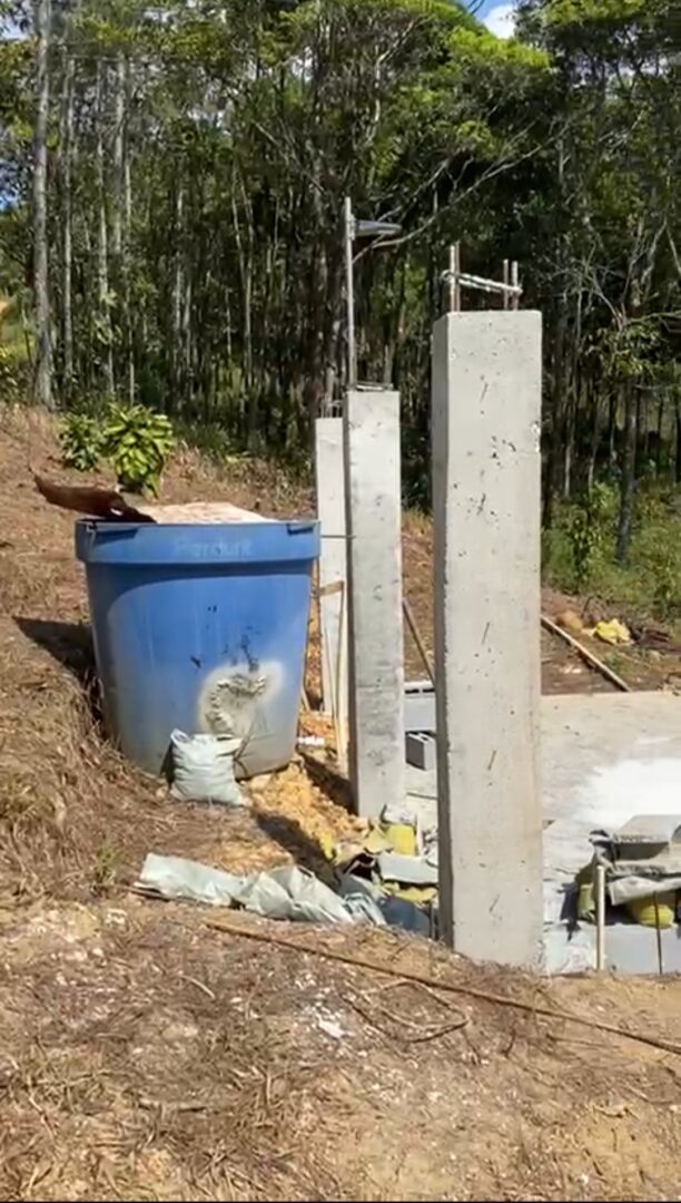 Concrete pillars set up at a construction site with a blue bucket nearby.